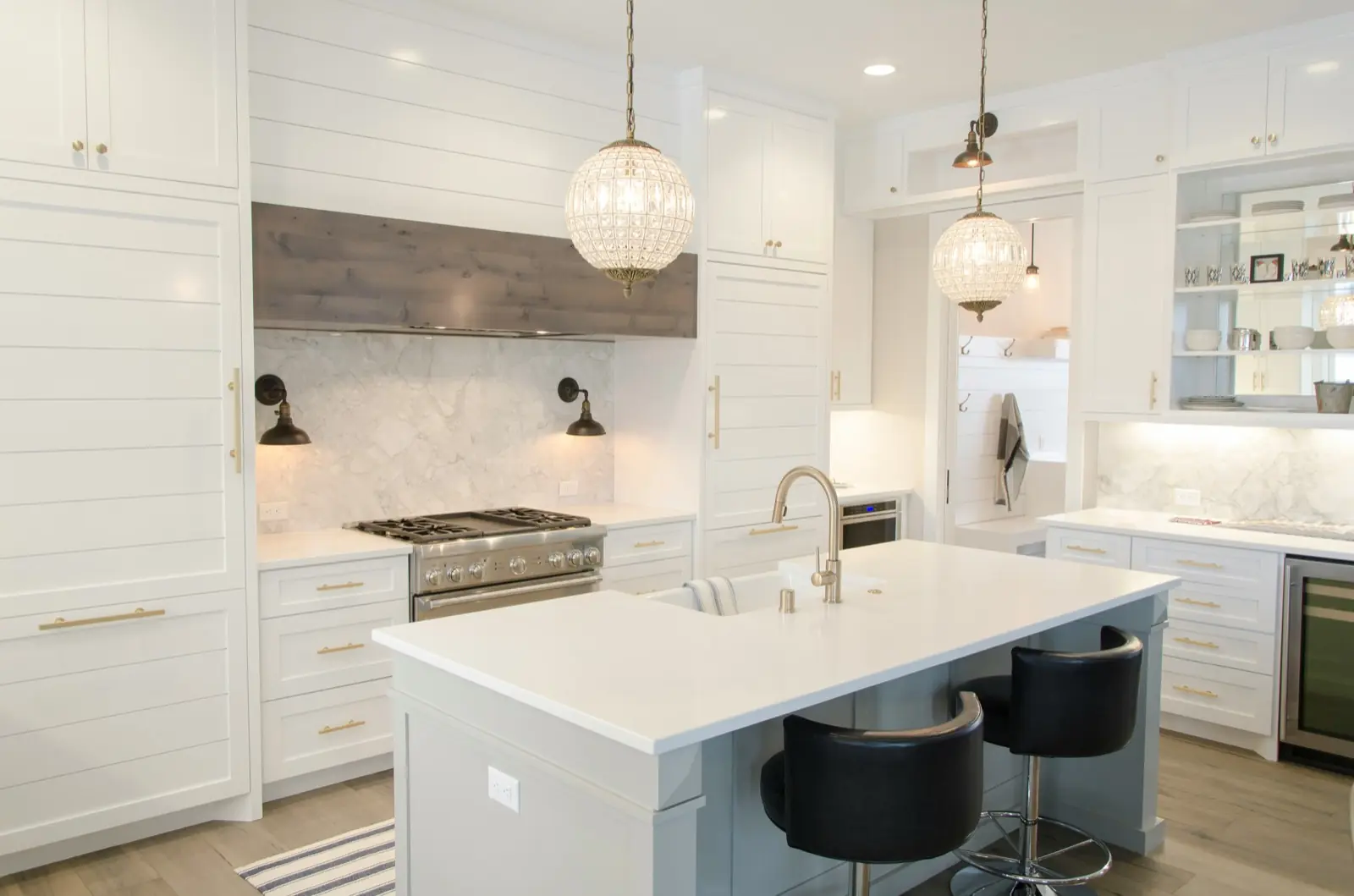 Bright white kitchen with a marble backsplash, gas range, and island seating