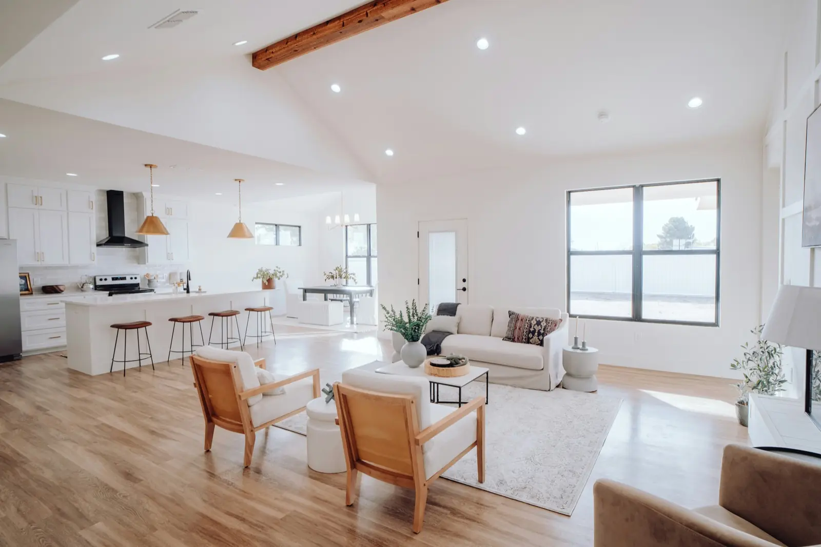 Open-plan living area and kitchen with light wood floors and large windows